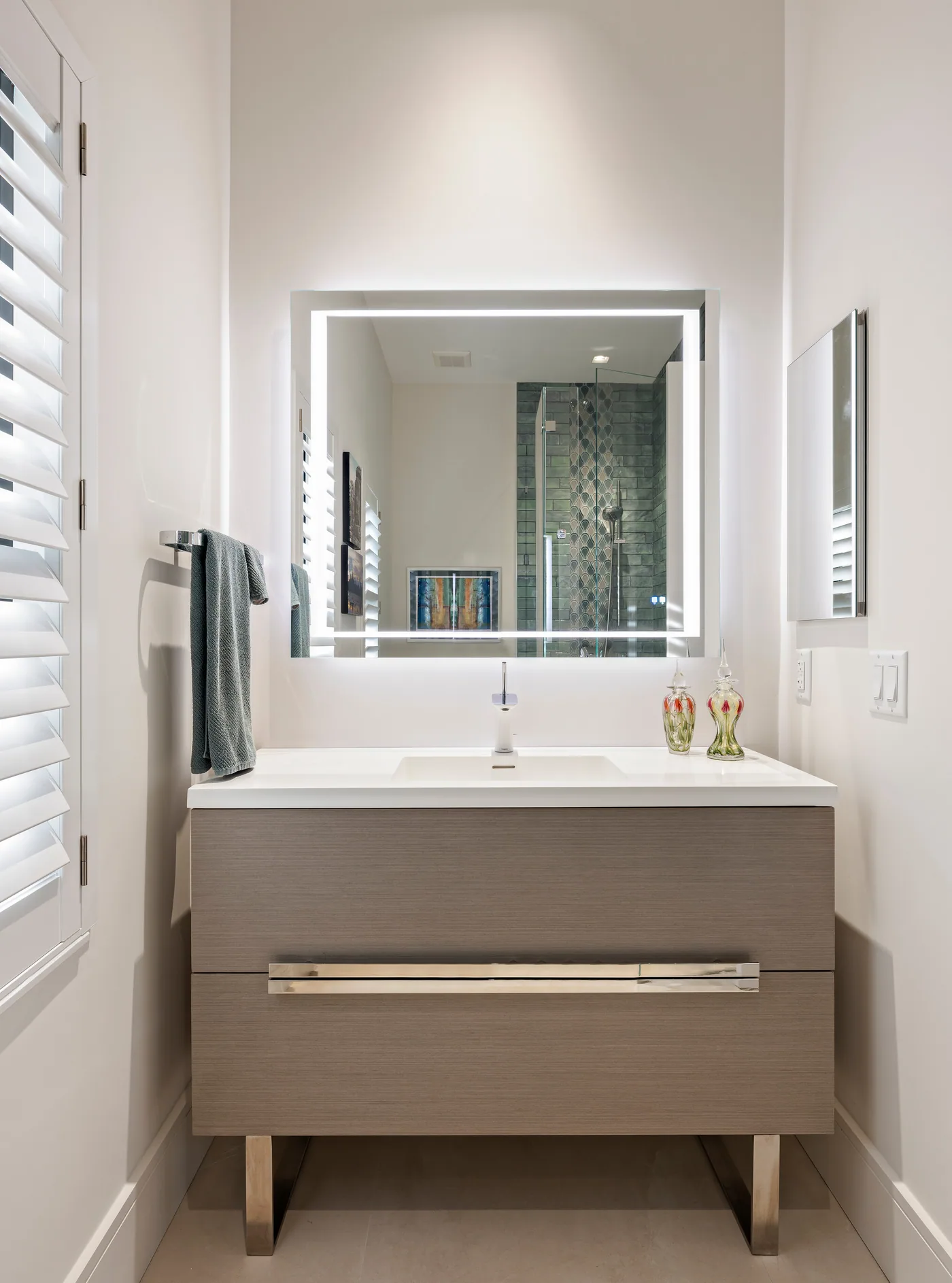 Custom floating vanity in grey oak with an integrated sink and backlit mirror