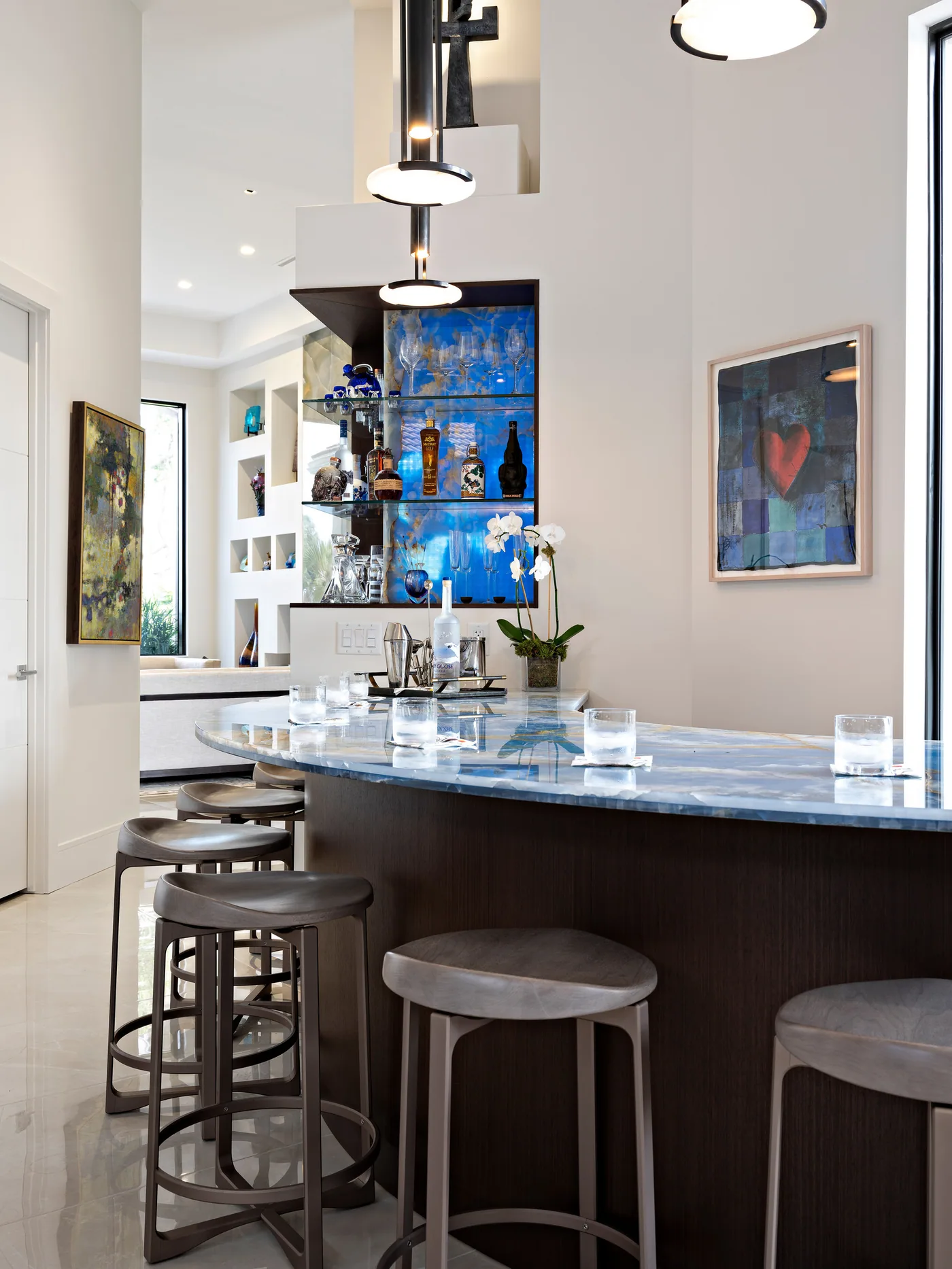 Curved custom bar in dark wood with a blue granite top and backlit display niche, Palm Beach County residence, Jupiter FL